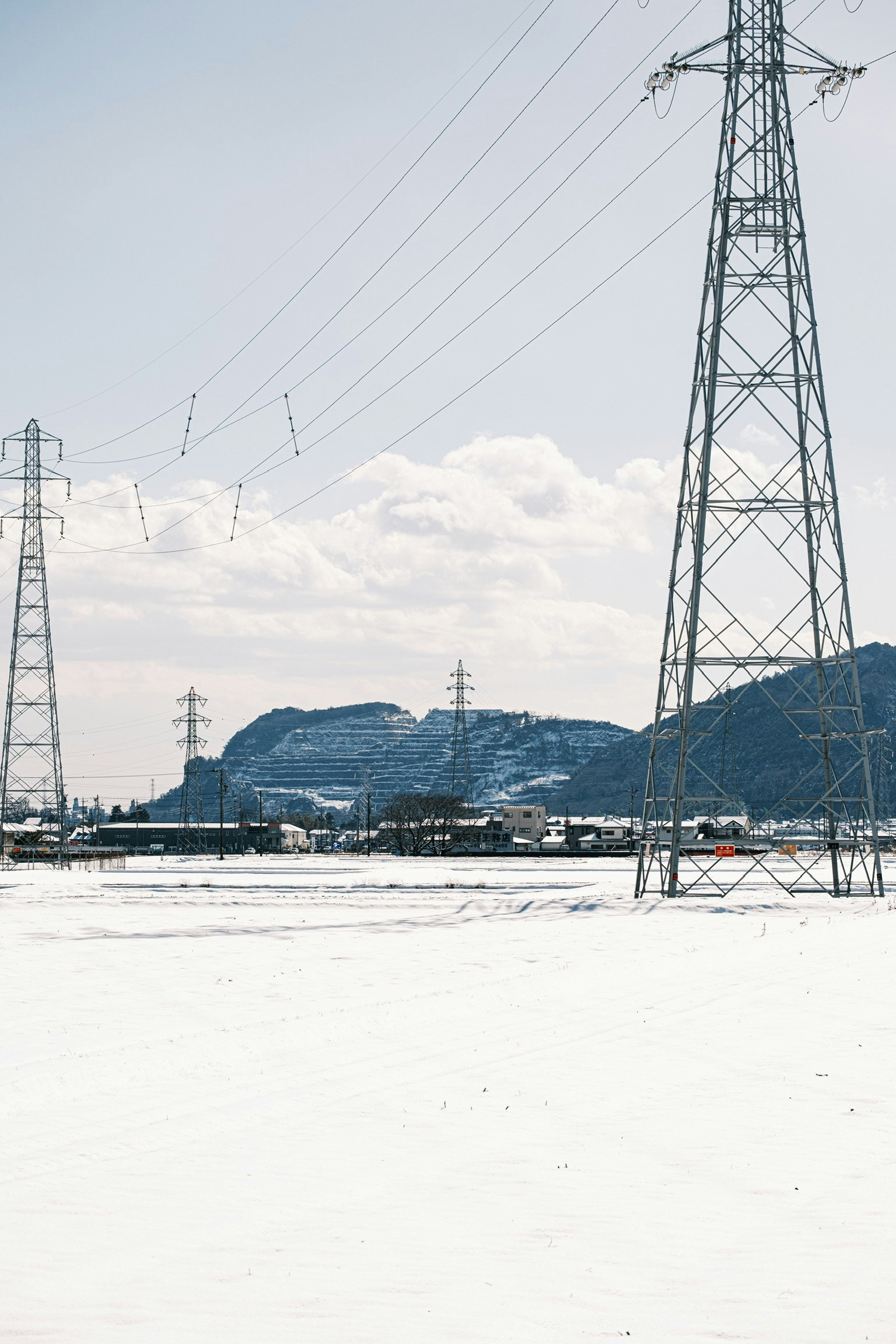 Paisaje nevado con líneas eléctricas y montañas al fondo