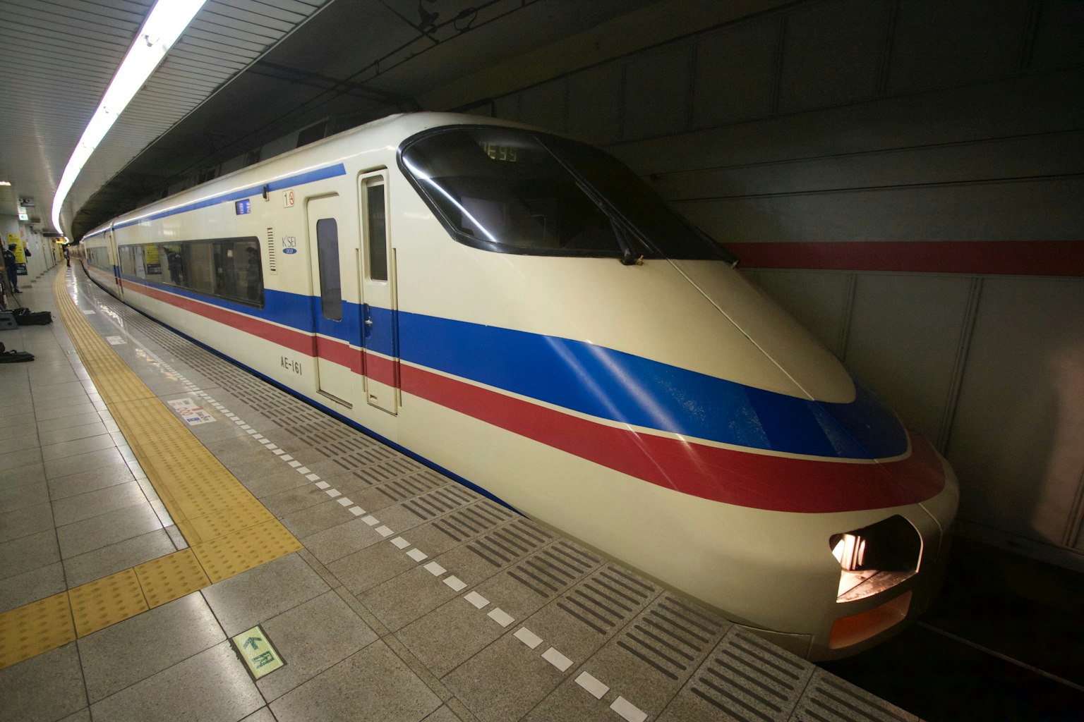 Tàu Shinkansen với sọc đỏ và xanh đặc trưng tại ga
