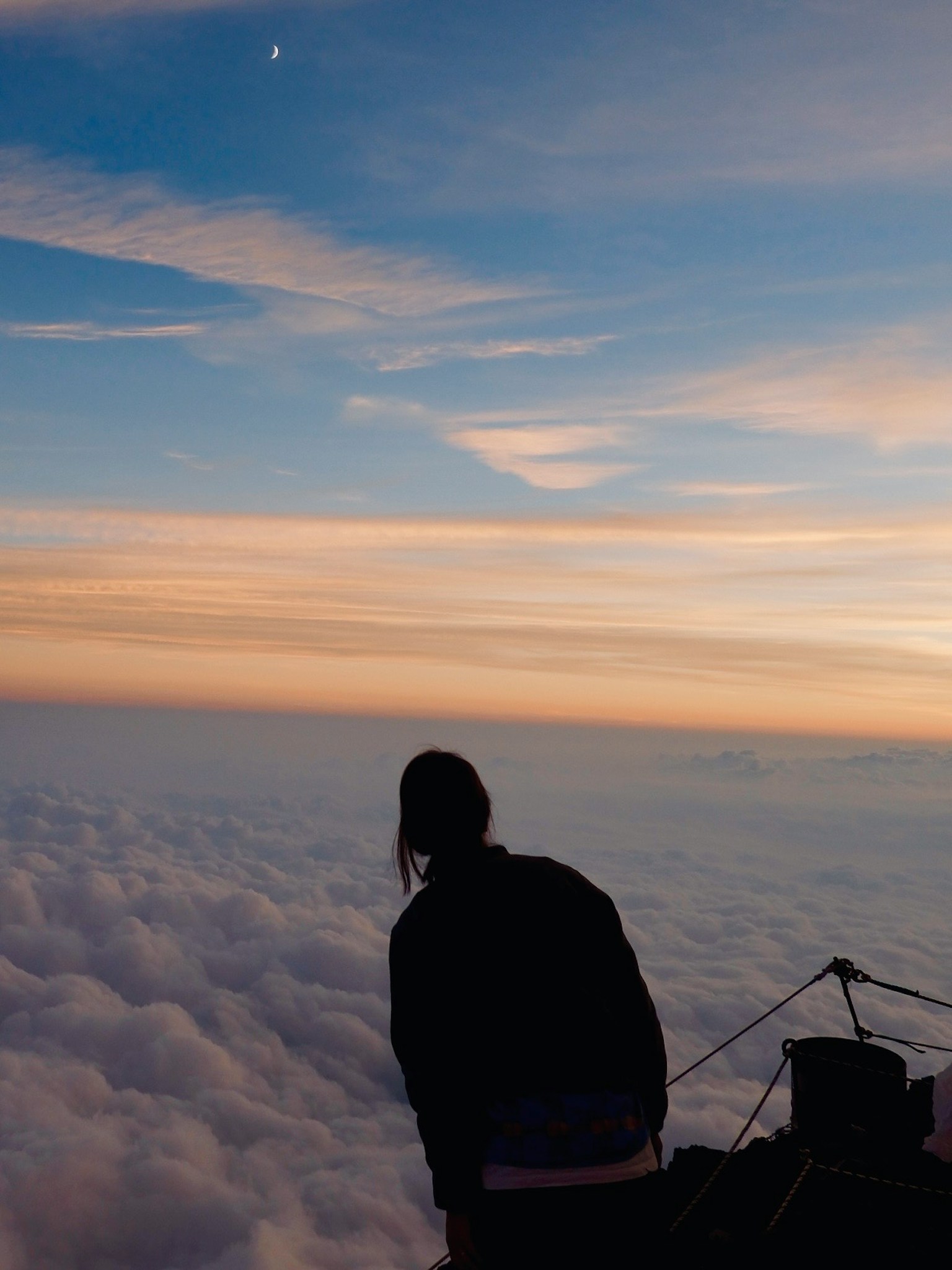 Person overlooking a sea of clouds with a beautiful sunset sky