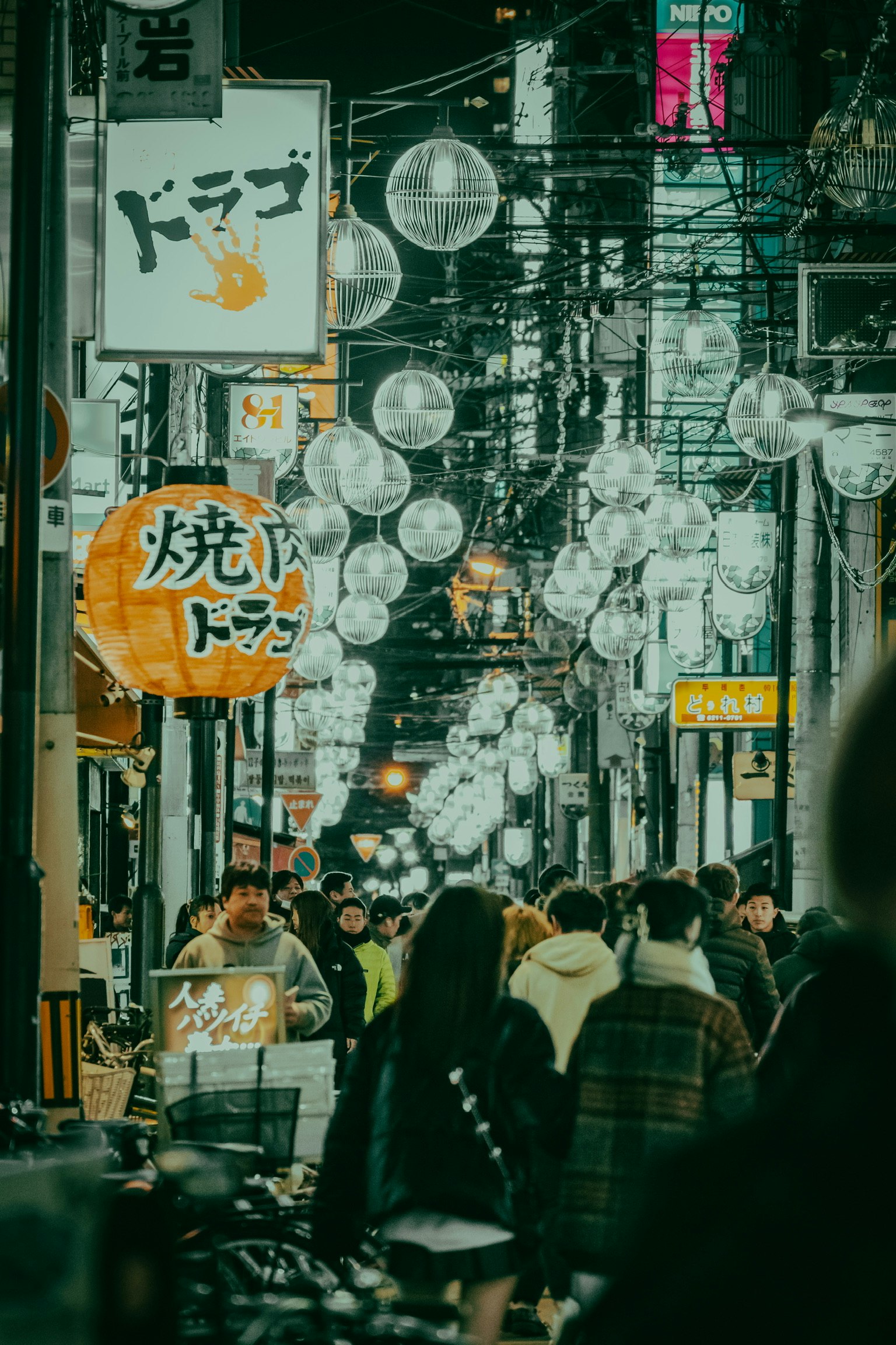 提灯が連なる夜の路地で人々が行き交う飲食街の風景