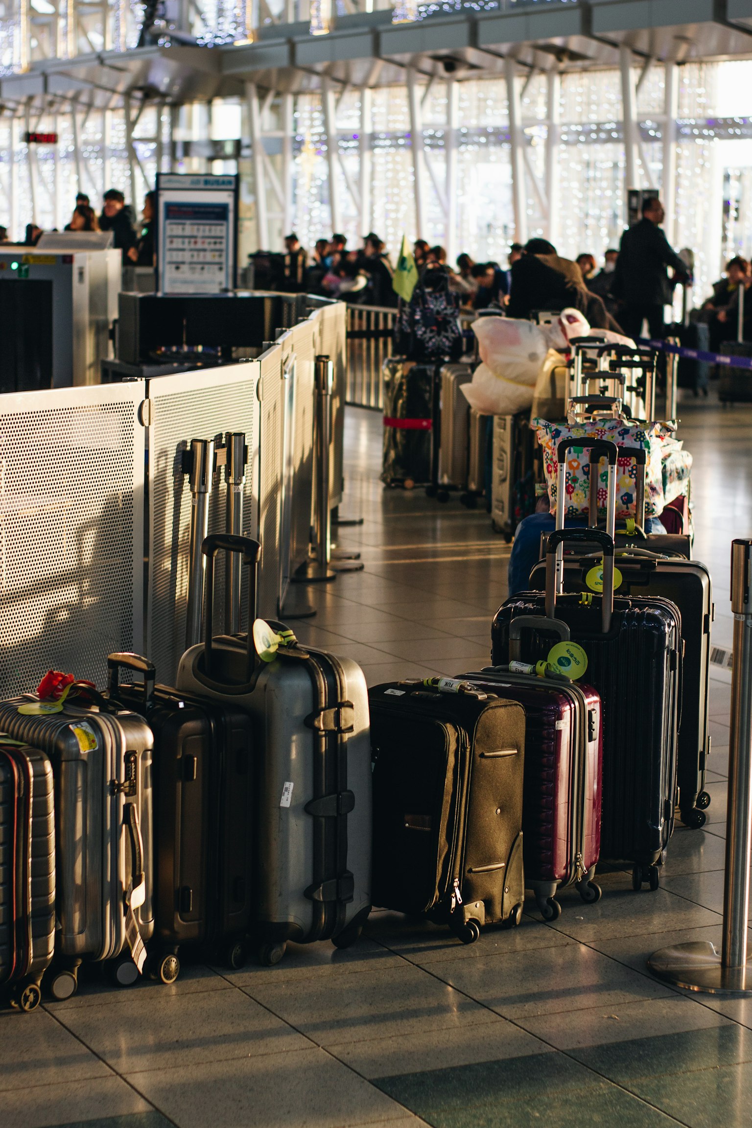 Una fila de equipaje en un área de facturación del aeropuerto con pasajeros al fondo