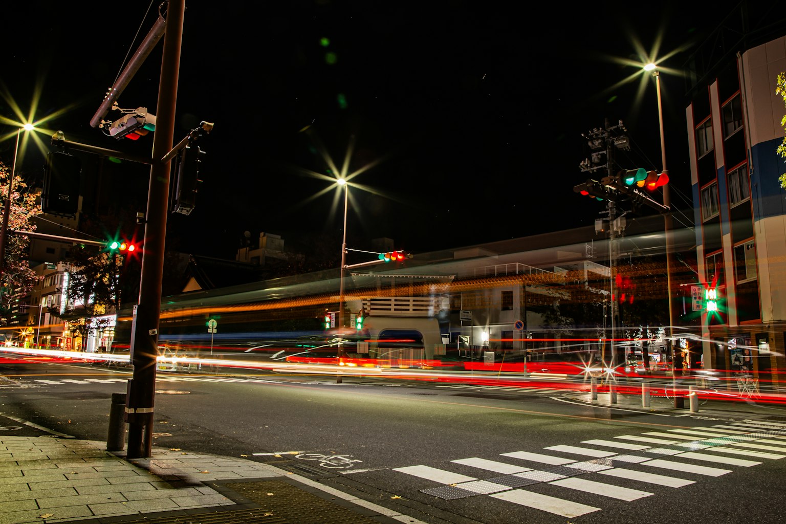 Persimpangan malam dengan jejak cahaya dari kendaraan dan lampu lalu lintas