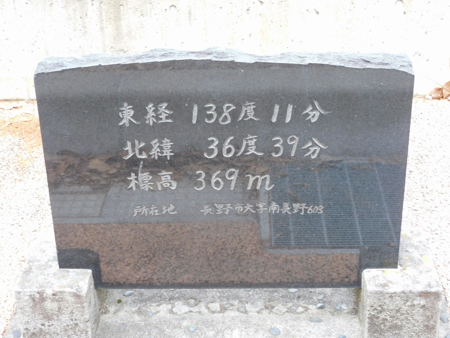 Schwarzes Steindenkmal mit Latitude- und Longitudekoordinaten