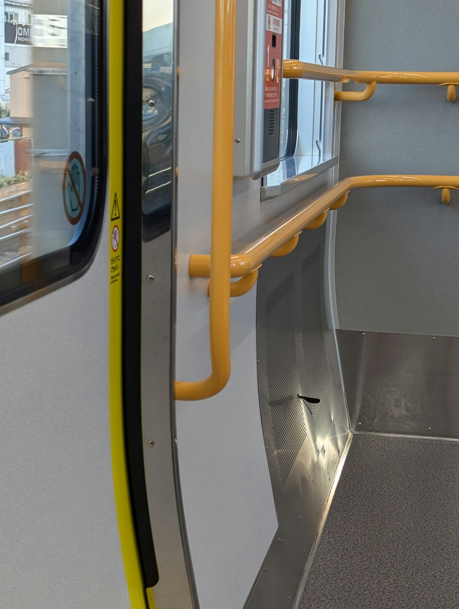 Interior de un tren de metro con pasamanos amarillos y paredes blancas
