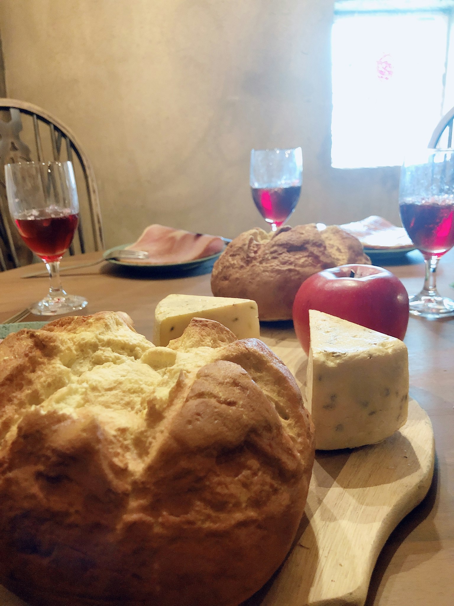 Roti, keju, apel, dan gelas anggur merah di atas meja kayu