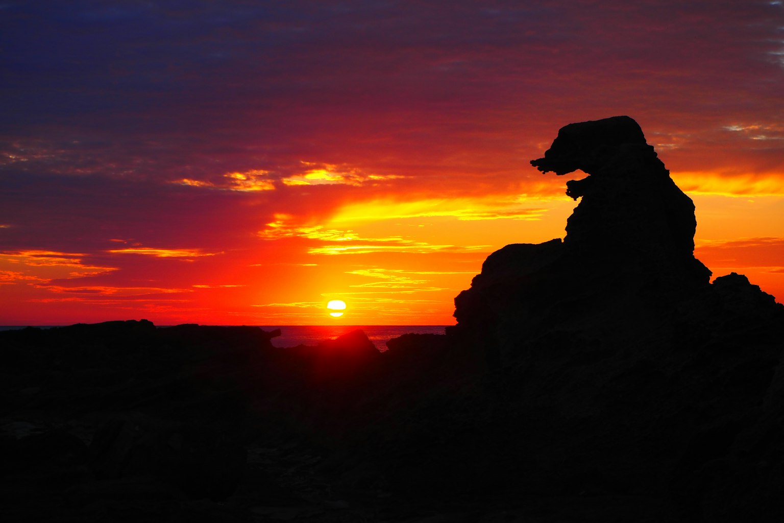 Silhouette einer Felsformation vor einem lebhaften Sonnenuntergang