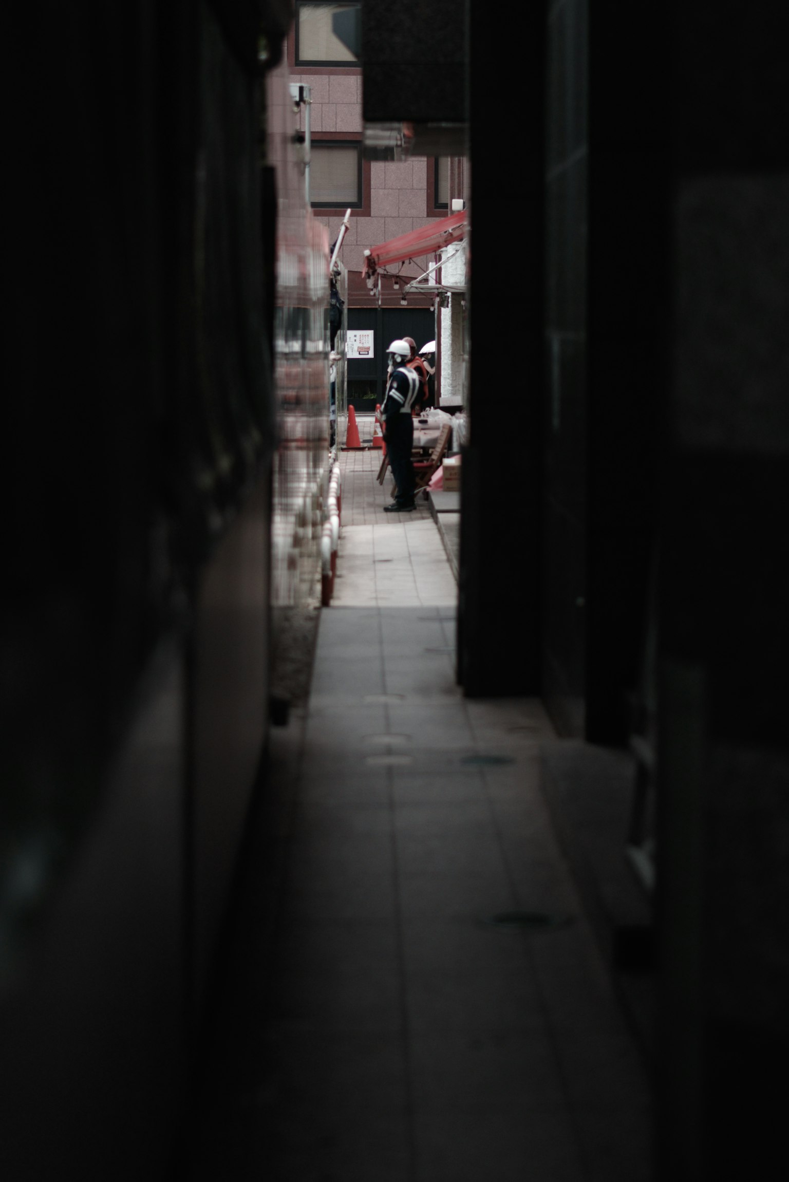 Eine Person steht in einer engen Gasse mit einem dunklen städtischen Hintergrund