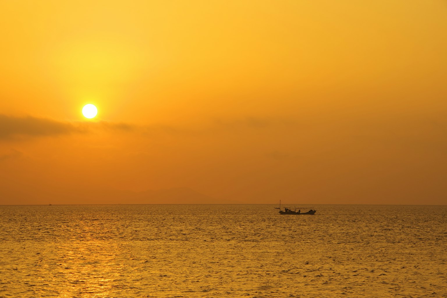 Silhouette di una piccola barca sull'oceano al tramonto