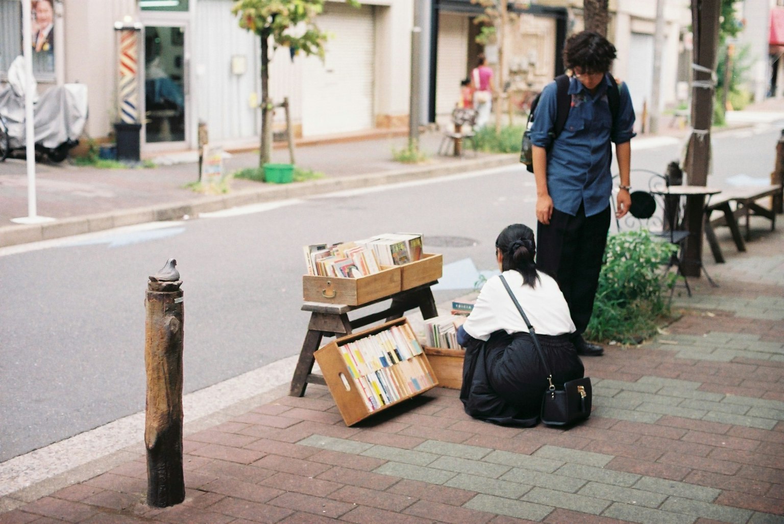 Une femme regardant des livres dans la rue avec un homme à proximité
