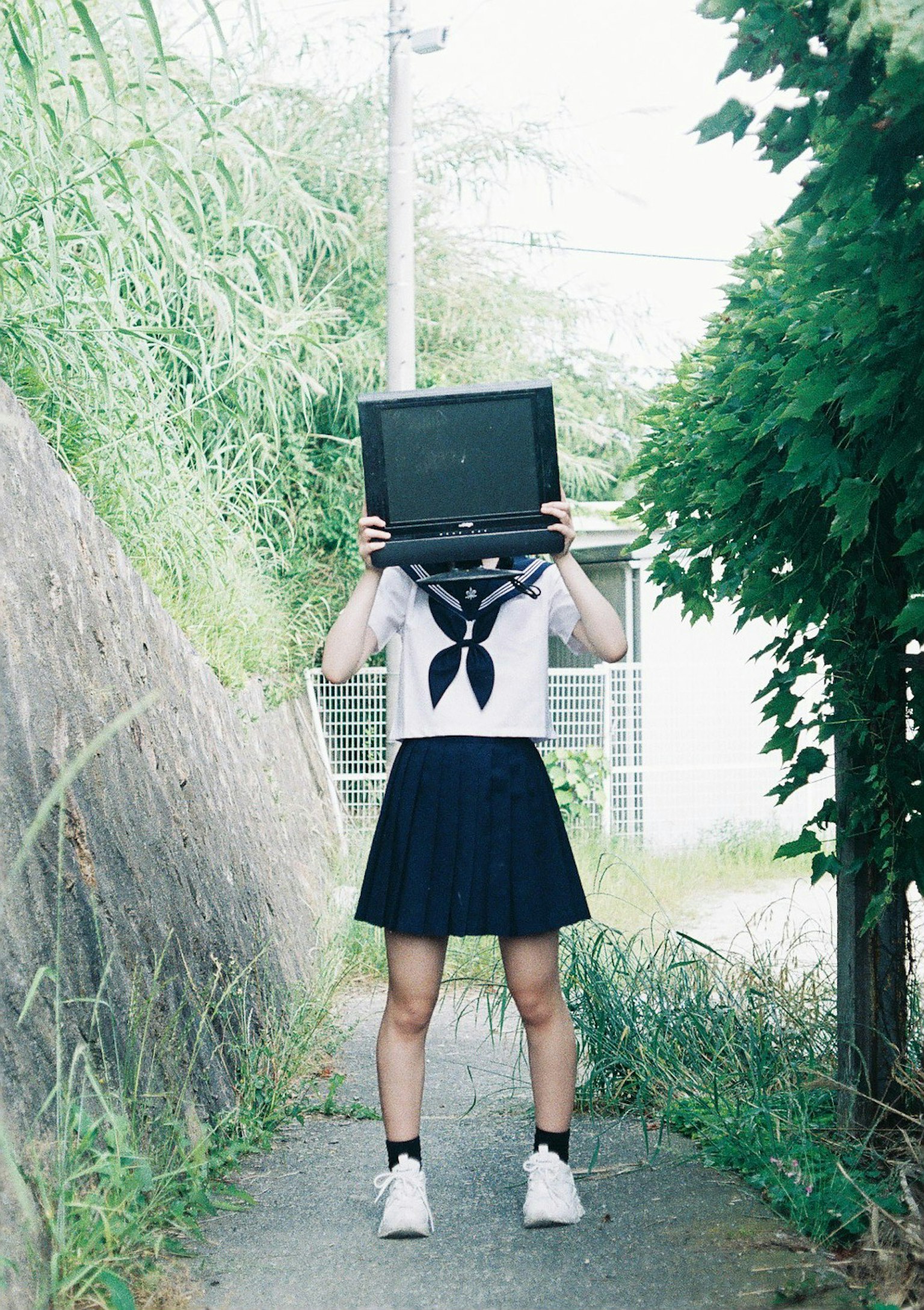 Una niña sosteniendo un televisor sobre su cabeza en un entorno exterior único