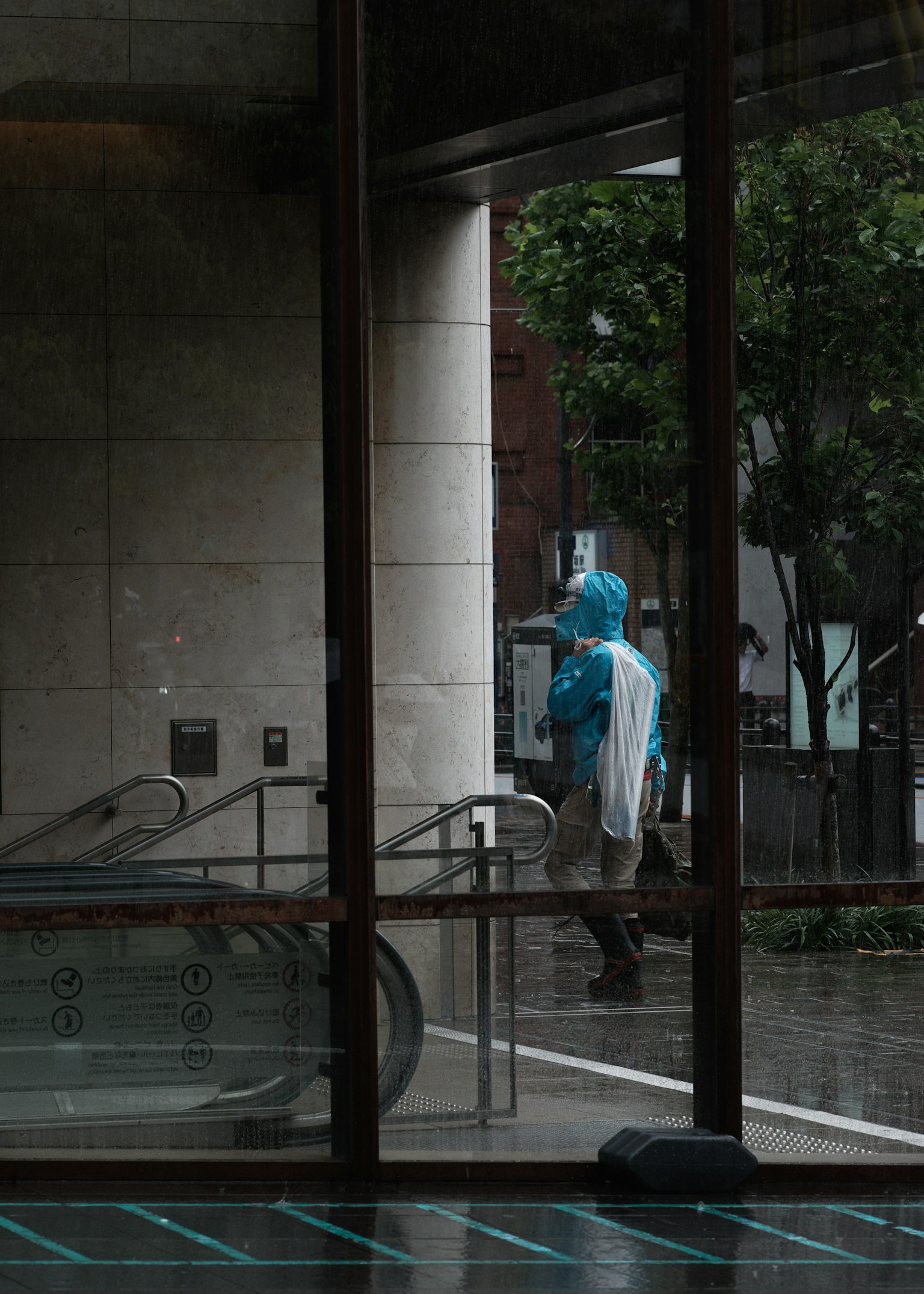 Una persona con un impermeable azul caminando afuera bajo la lluvia