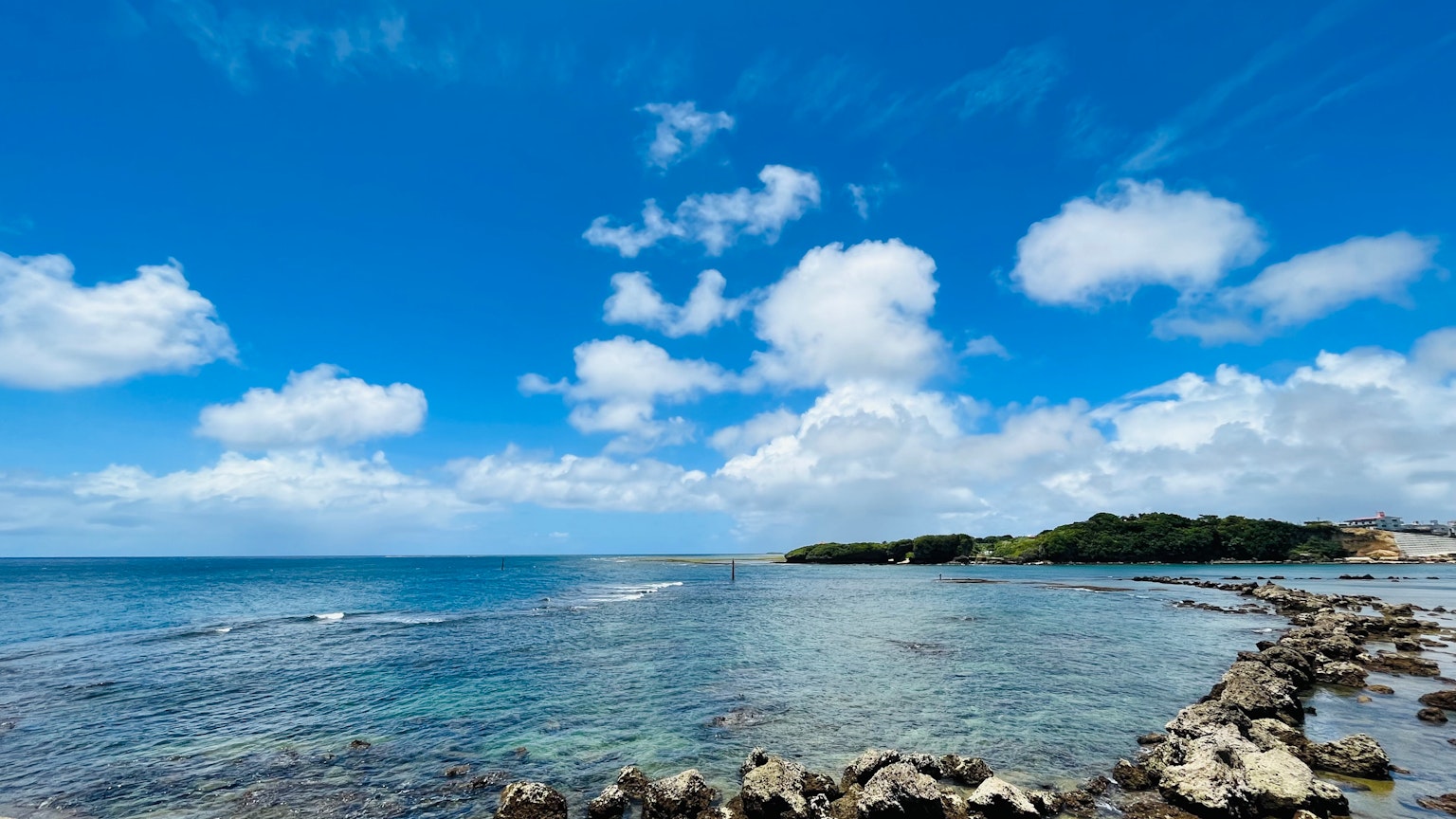 蓝色海洋在明亮天空和白云下的风景 岩石海岸线在前景中