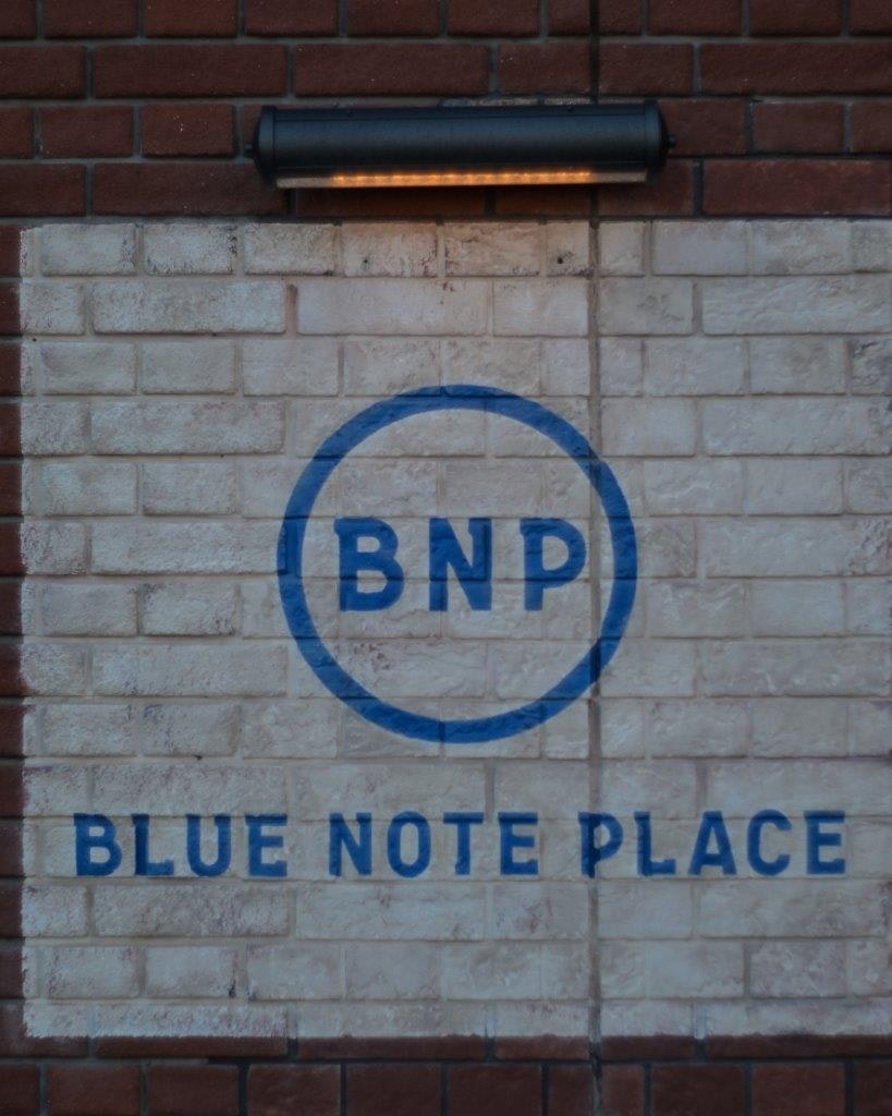 レンガ壁にあるBNPとBLUE NOTE PLACEの看板