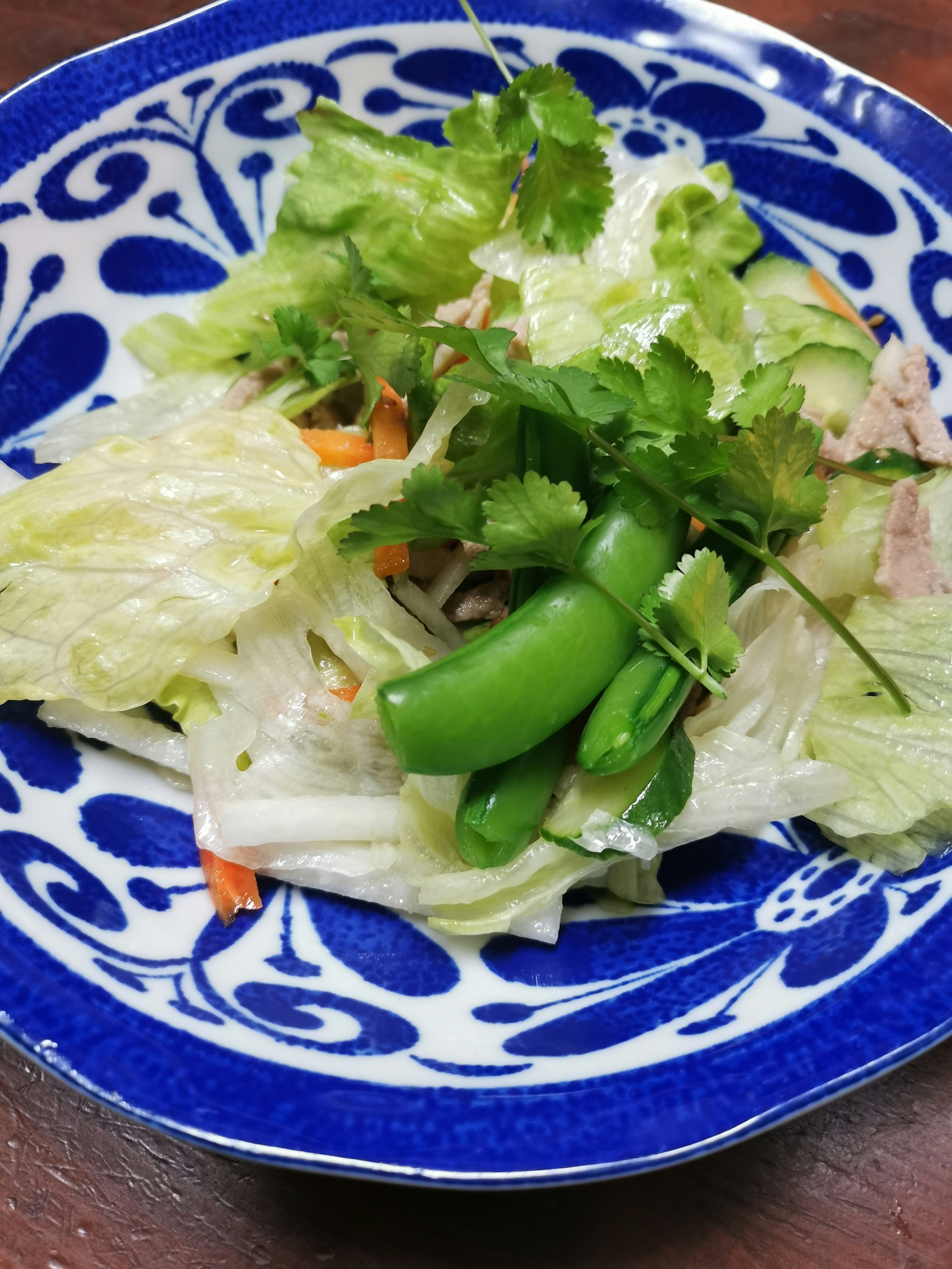 青い柄の皿に盛られた白菜と鶏肉のサラダ