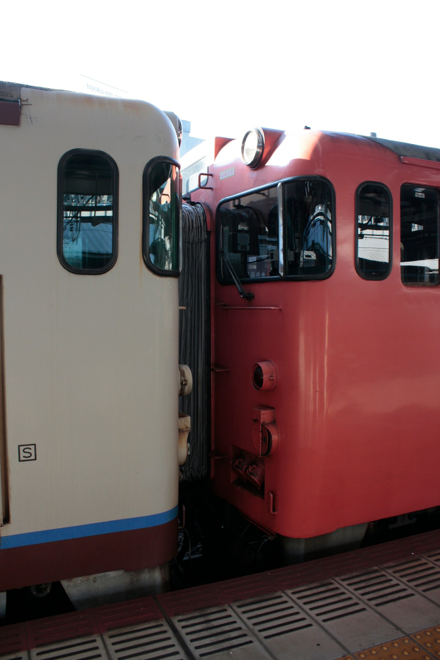 สองรถไฟอยู่ใกล้กันหนึ่งขาวและหนึ่งแดง