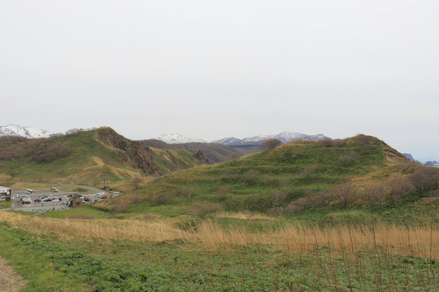 Pemandangan dengan bukit hijau dan padang rumput dengan pemukiman kecil