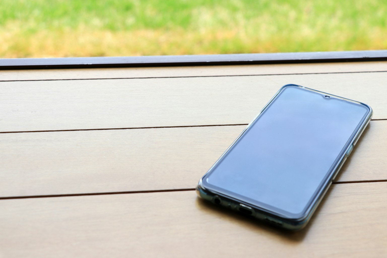 Smartphone posé sur une table en bois avec un arrière-plan vert