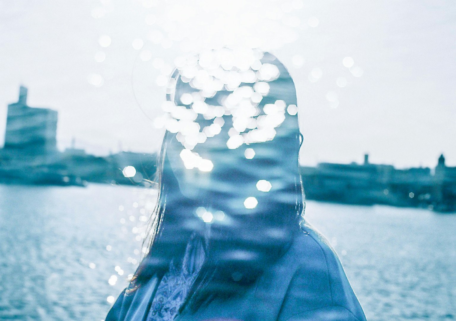 Silhouette di una donna con la luce del sole riflessa sull'acqua dietro di lei