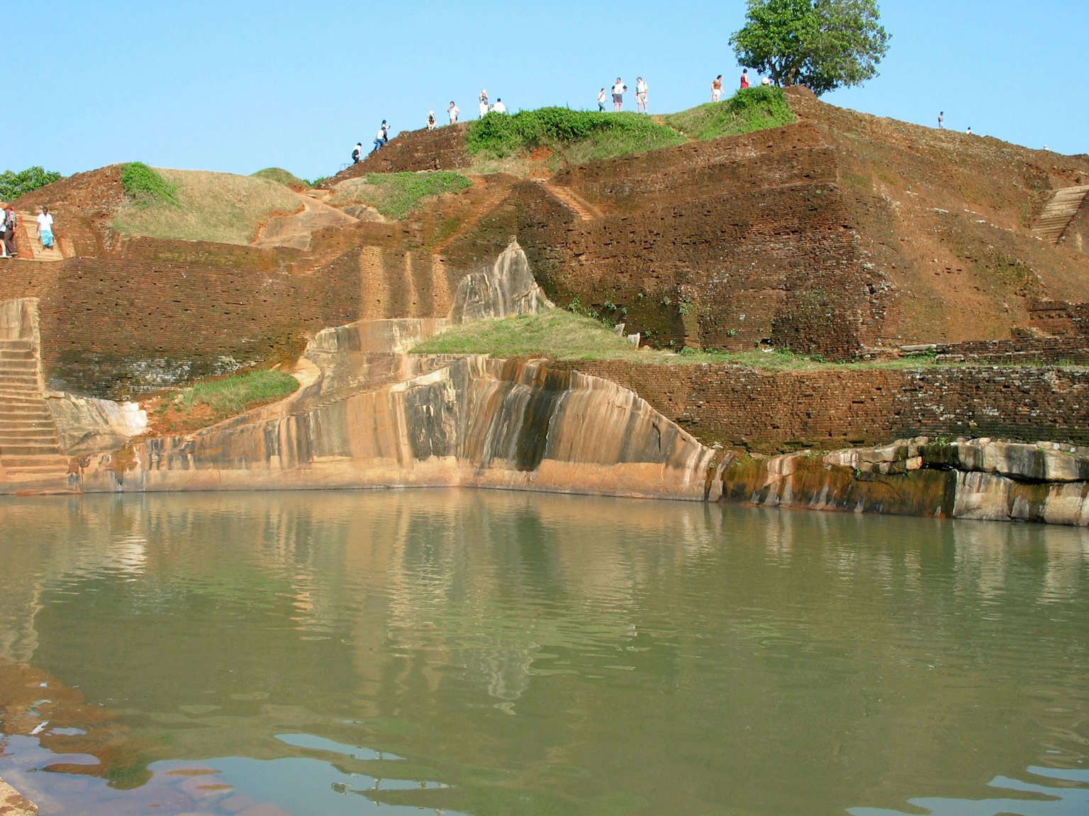 Ruhige Wasseroberfläche mit einer Klippe und grünen Bäumen im Hintergrund