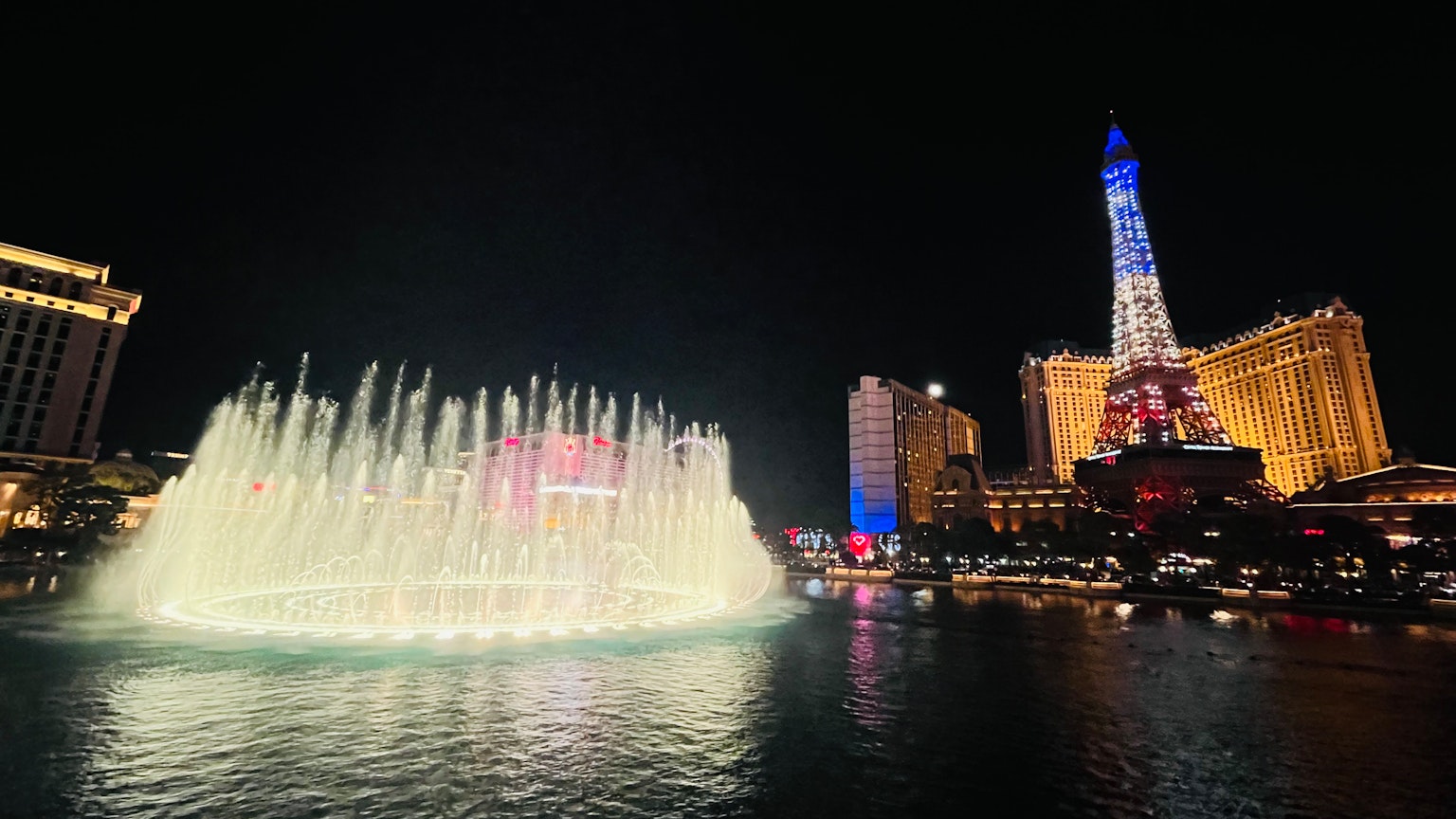 Brunnen-Show in Las Vegas bei Nacht mit beleuchtetem Eiffelturm