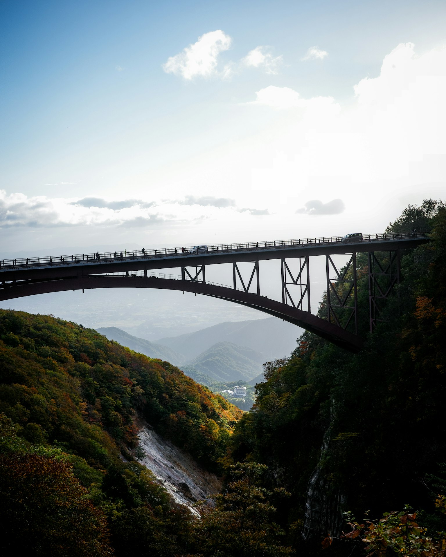 Un hermoso puente de hierro que atraviesa un valle montañoso con luz solar iluminando la escena