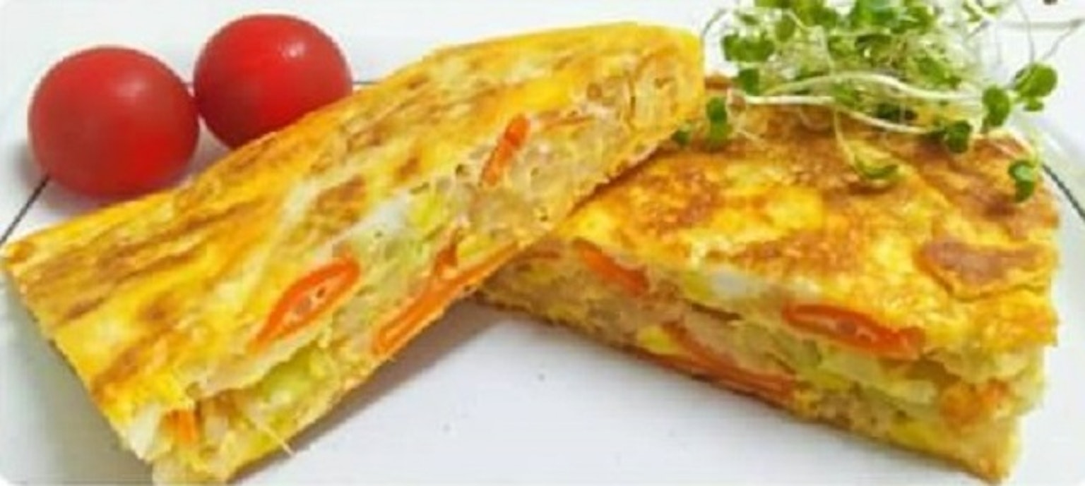 Deliziosa omelette tagliata a metà servita con pomodori rossi e germogli