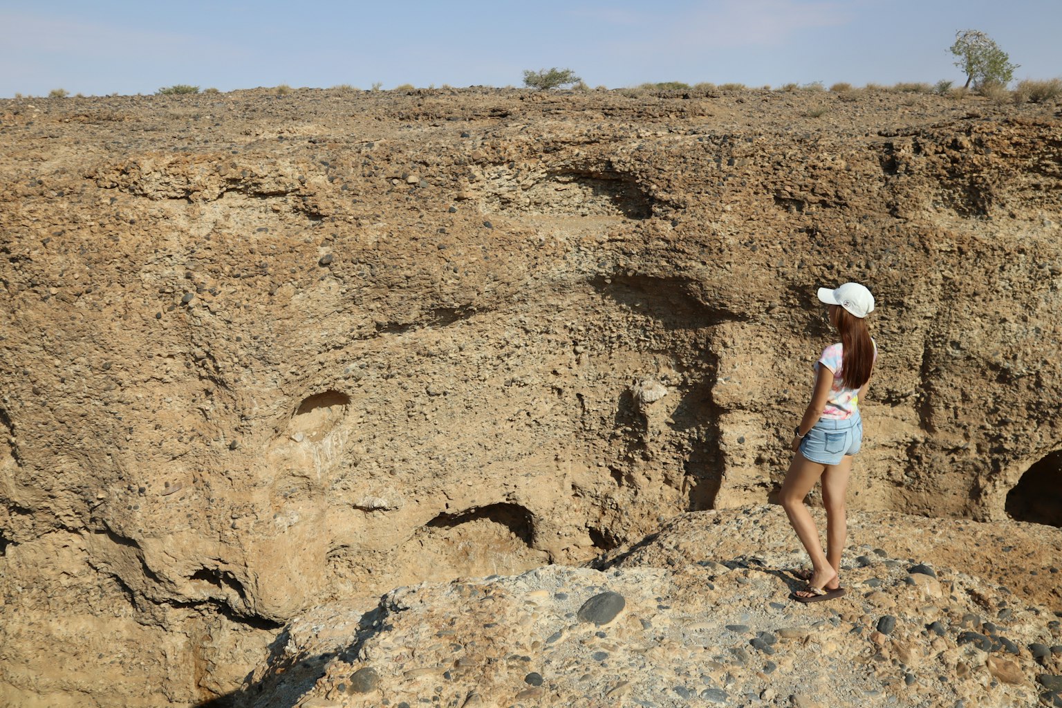 Frau steht auf felsigem Terrain mit trockenem braunem Landschaft