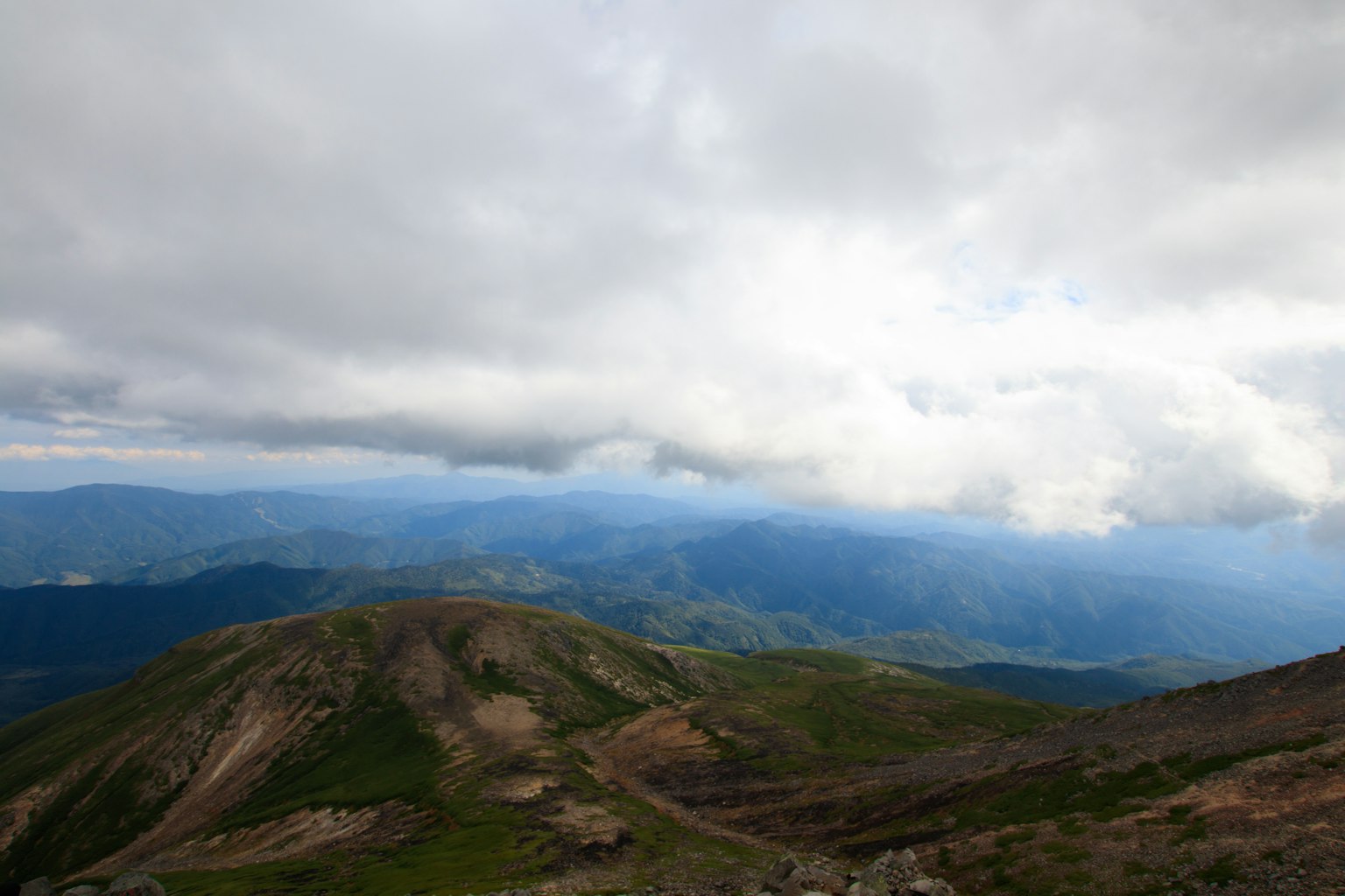 Mountain landscape with cloudy sky green hills and distant mountains