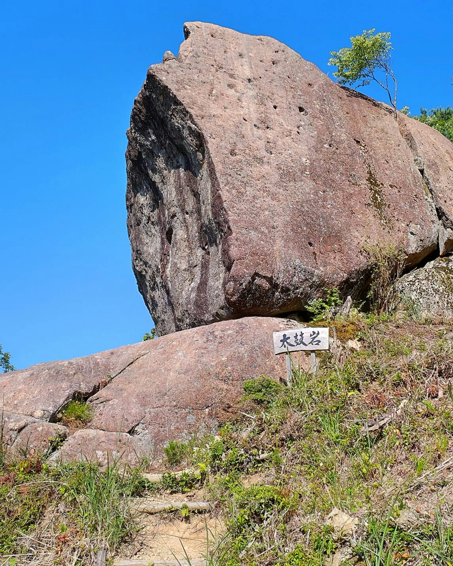 Großer Felsen mit einem Schild vor blauem Himmel