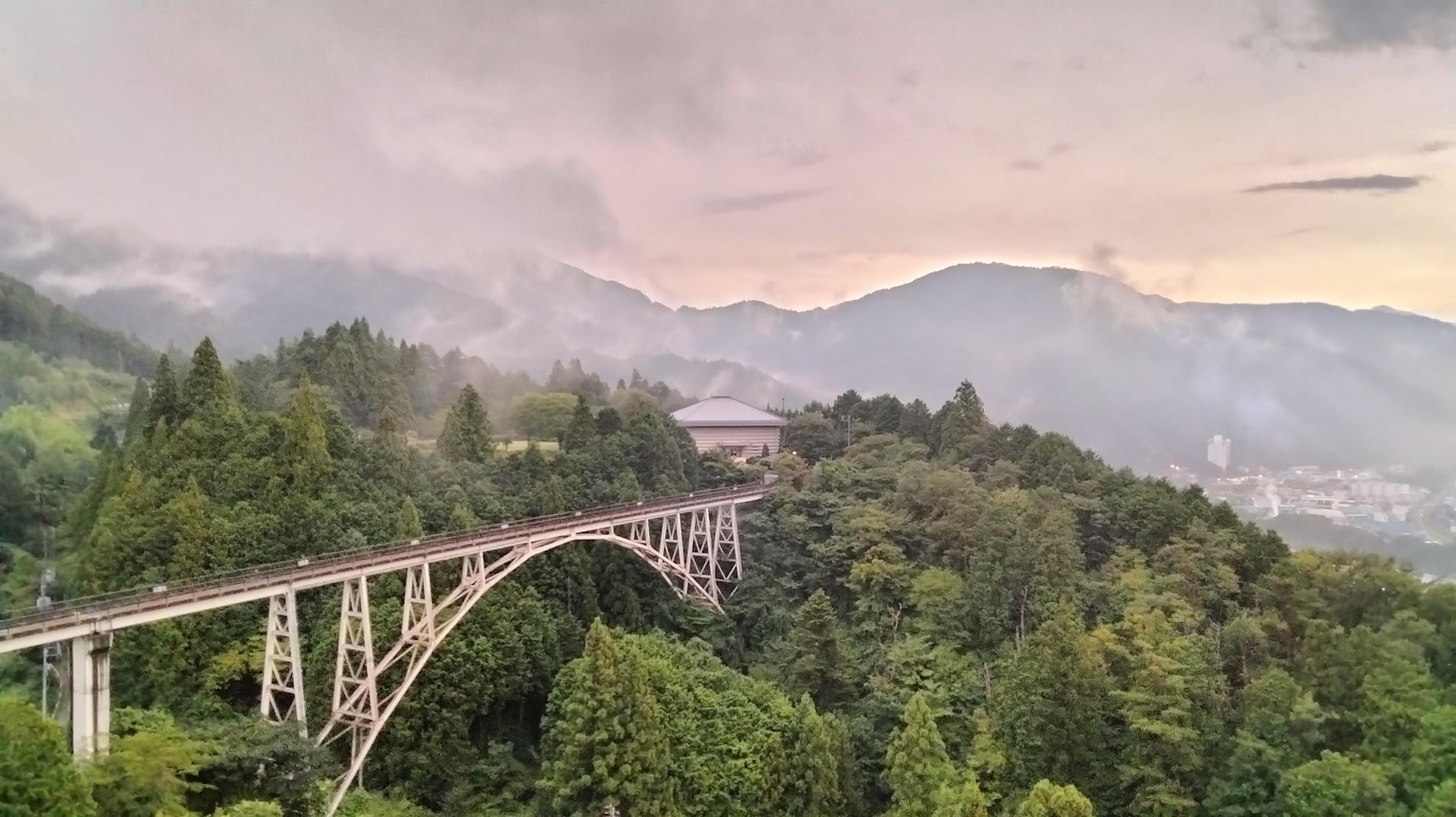 สะพานที่ถูกล้อมรอบด้วยภูเขาและทิวทัศน์ที่มีหมอก