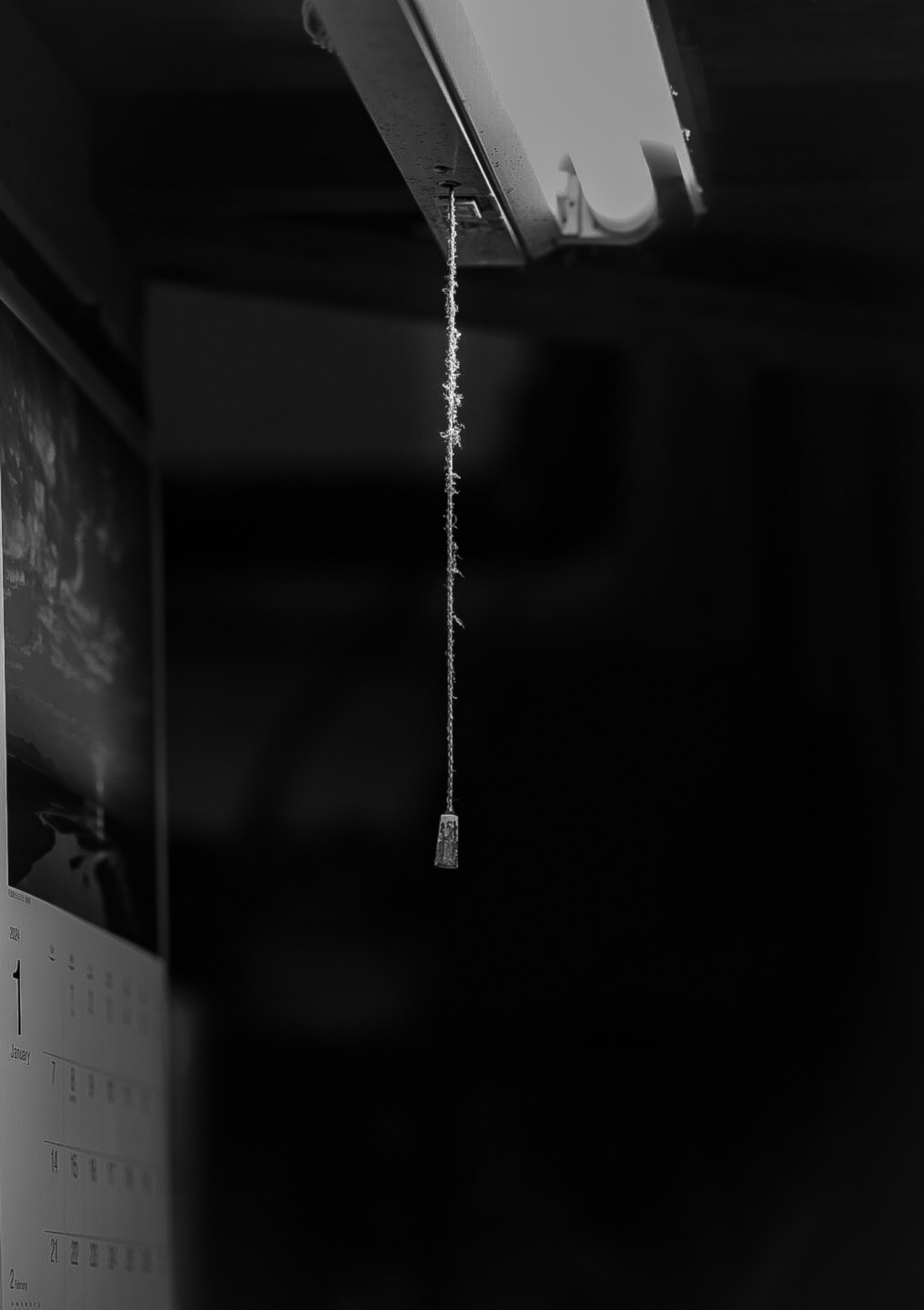 Light switch cord hanging in a dark room