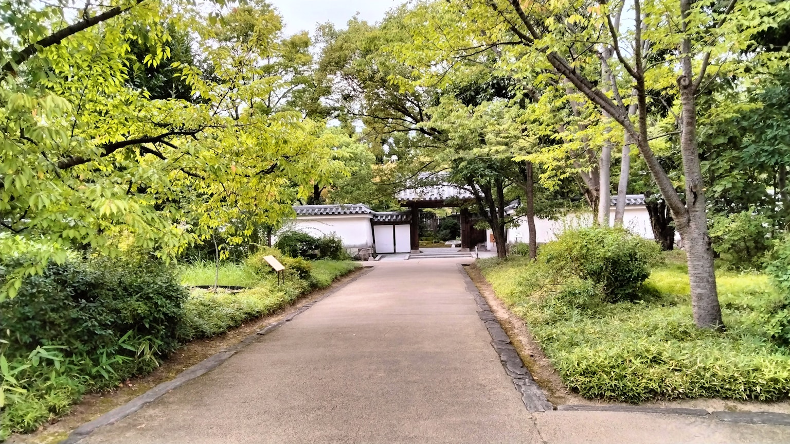 一条宁静的小道穿过郁郁葱葱的绿地通向一座白墙建筑