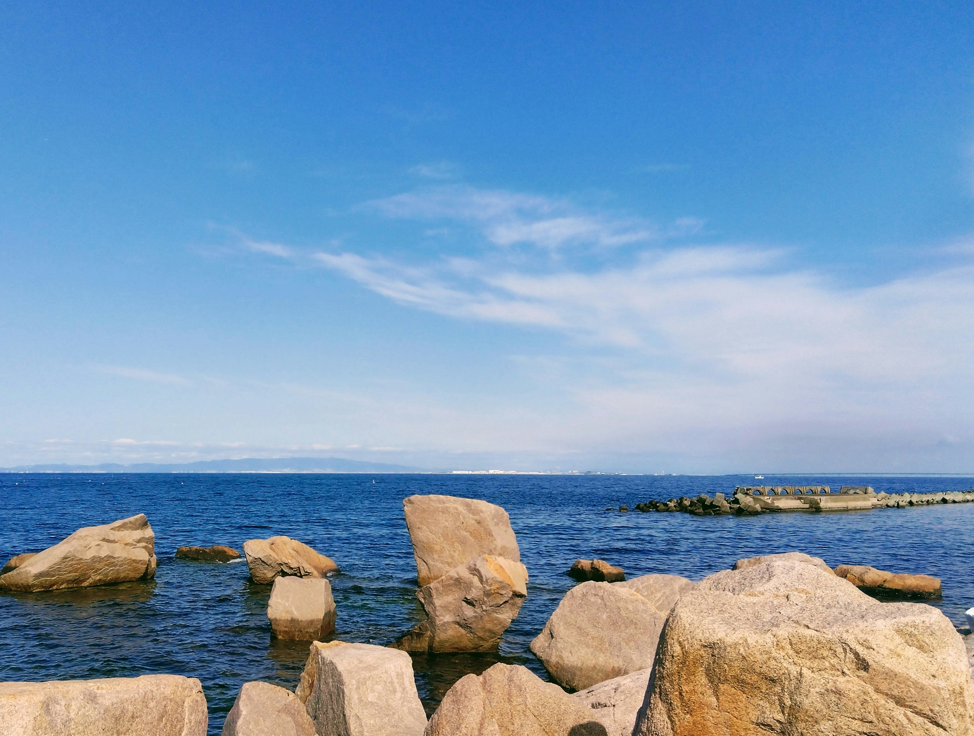 Rocce lungo una costa tranquilla con un’isola lontana