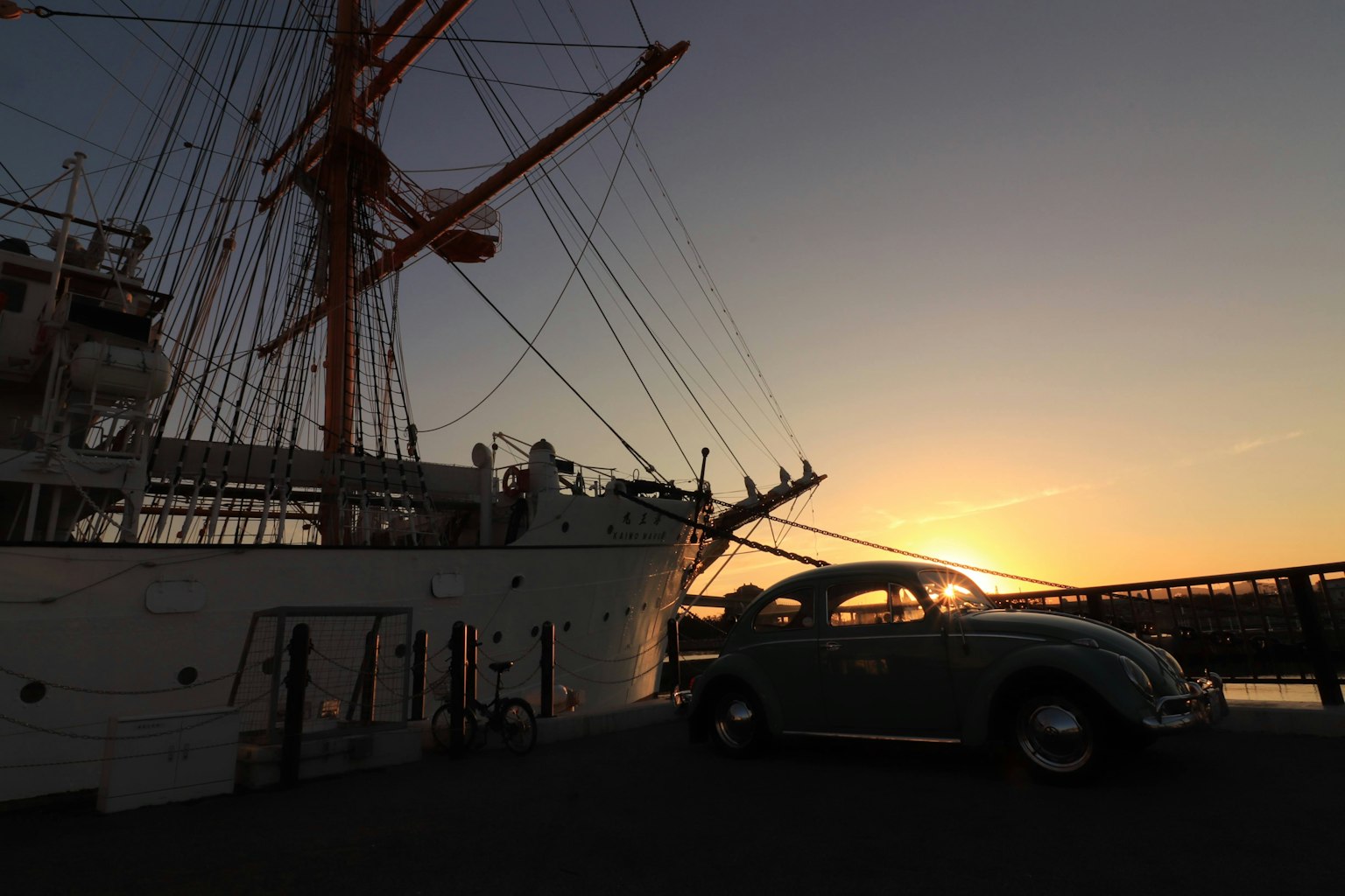 Silhouette d'un bateau et d'une voiture Beetle au coucher du soleil