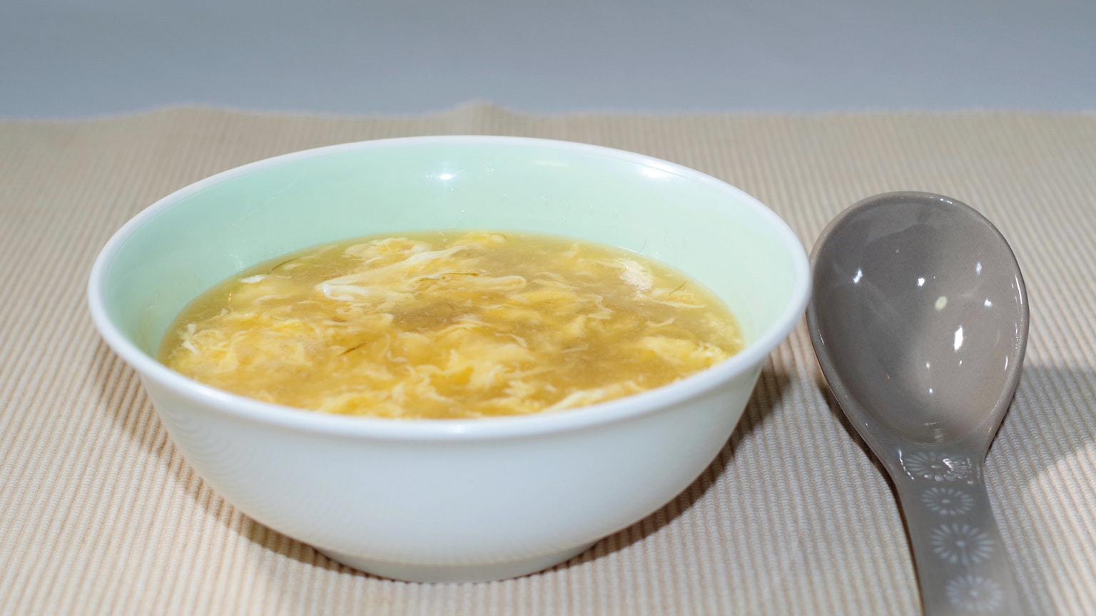 淺綠色碗中的蛋湯和灰色湯匙