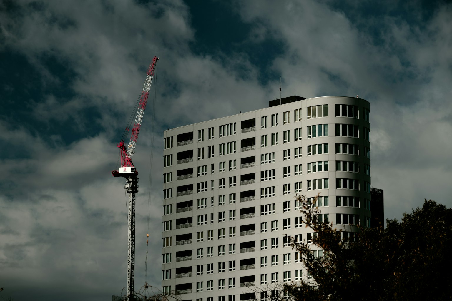 Edificio de gran altura con una grúa bajo un cielo oscuro