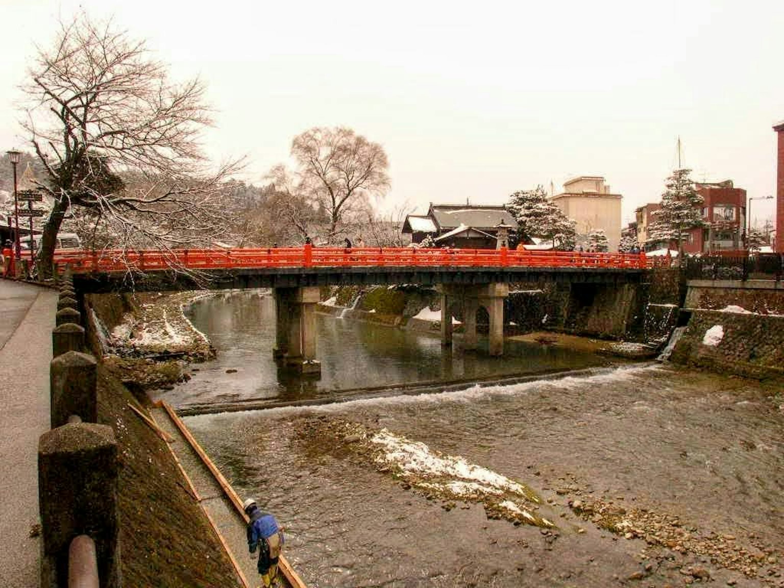 Vista panoramica di un fiume innevato con un ponte rosso