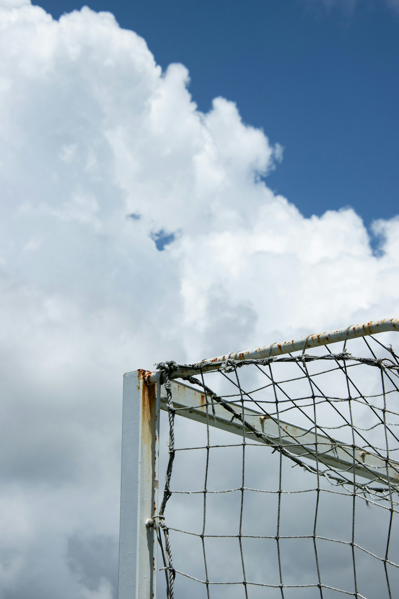 Bagian dari gawang sepak bola di bawah langit biru dengan awan