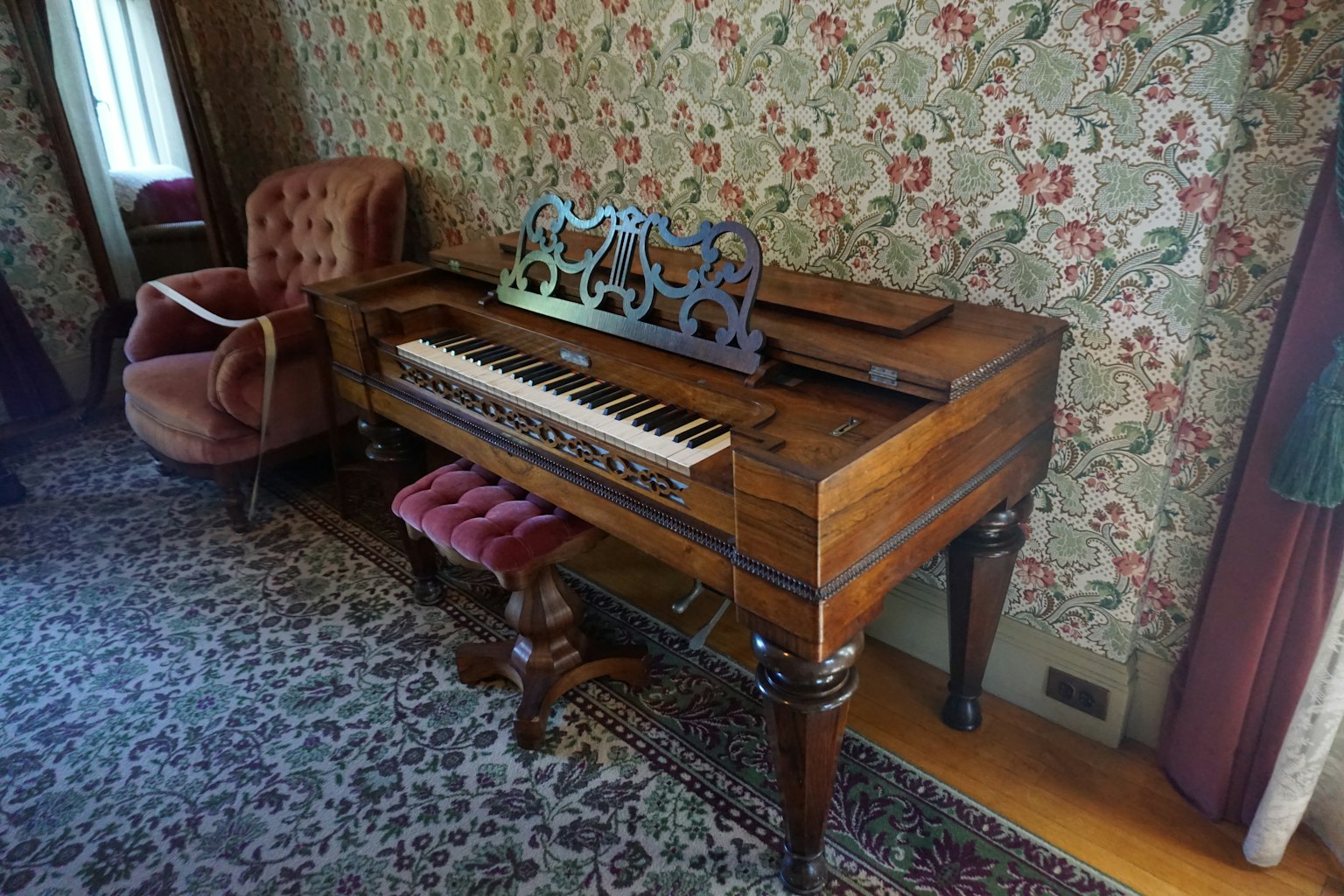 Piano antico con una sedia rossa in un interno vintage