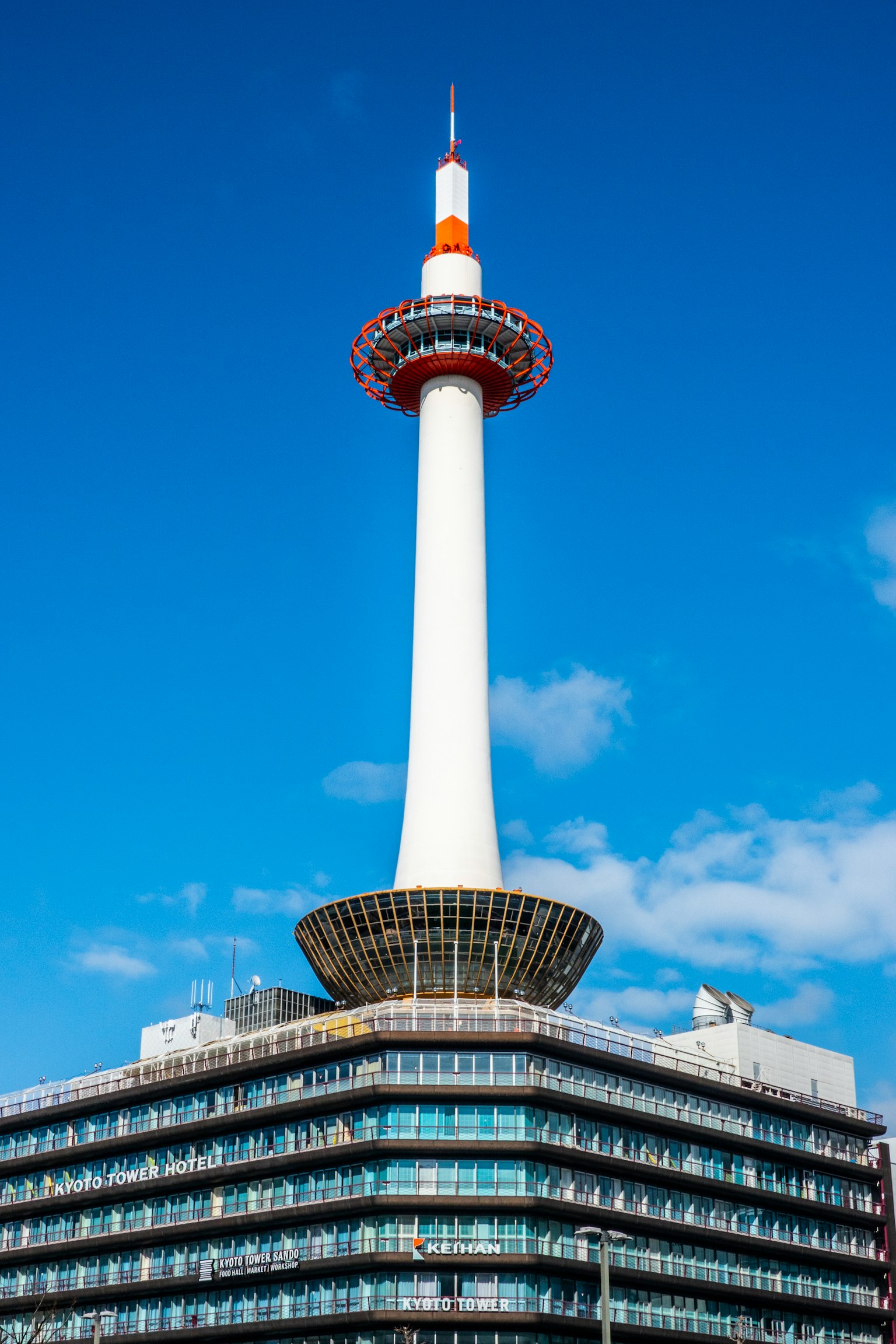 Menara Kyoto dengan struktur putih dan aksen merah di bawah langit biru