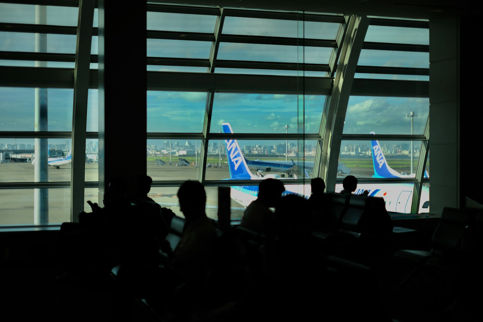 空港の待合室から見える飛行機の尾翼と窓のシルエット