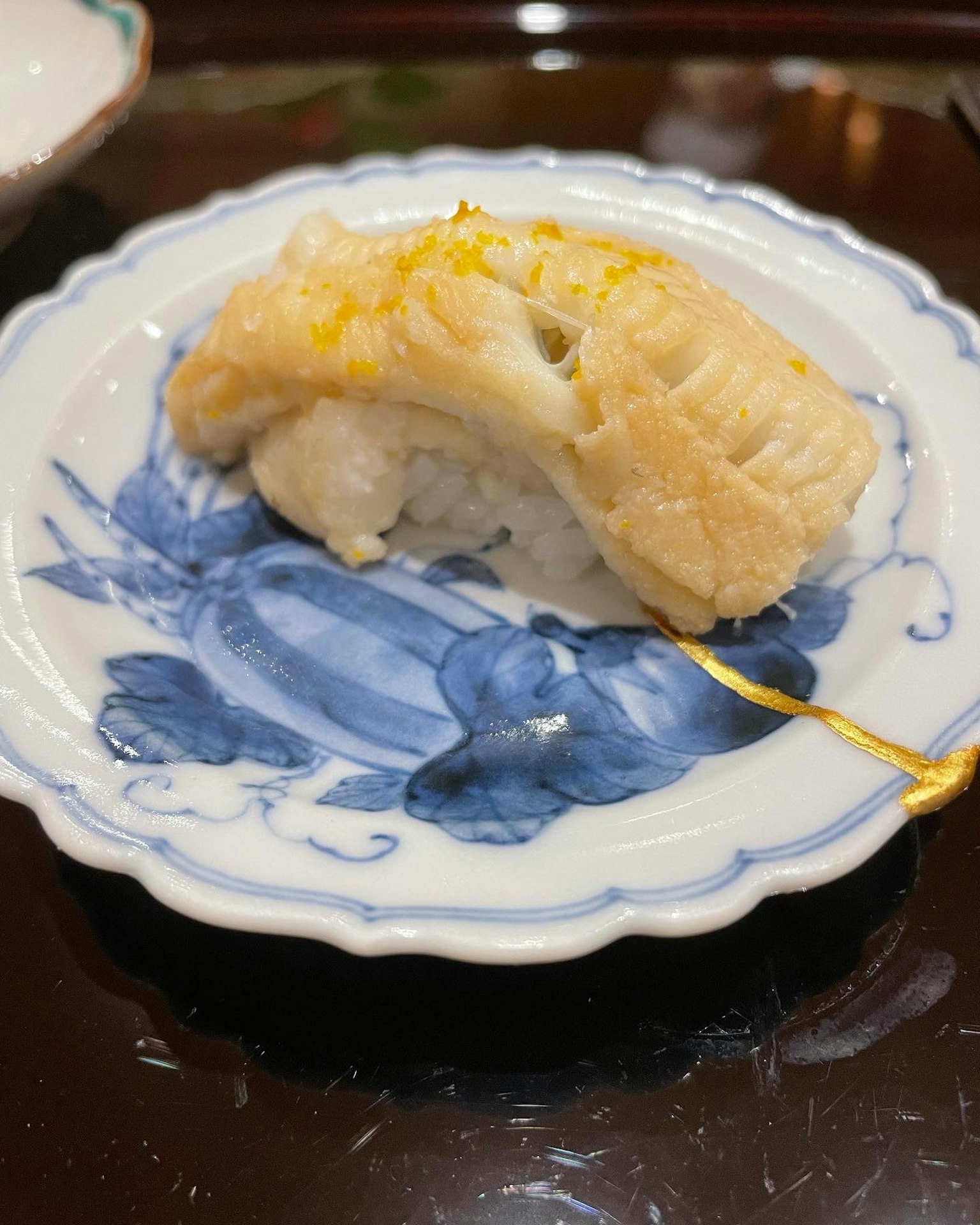 Sushi cá nướng trên đĩa trắng với họa tiết xanh