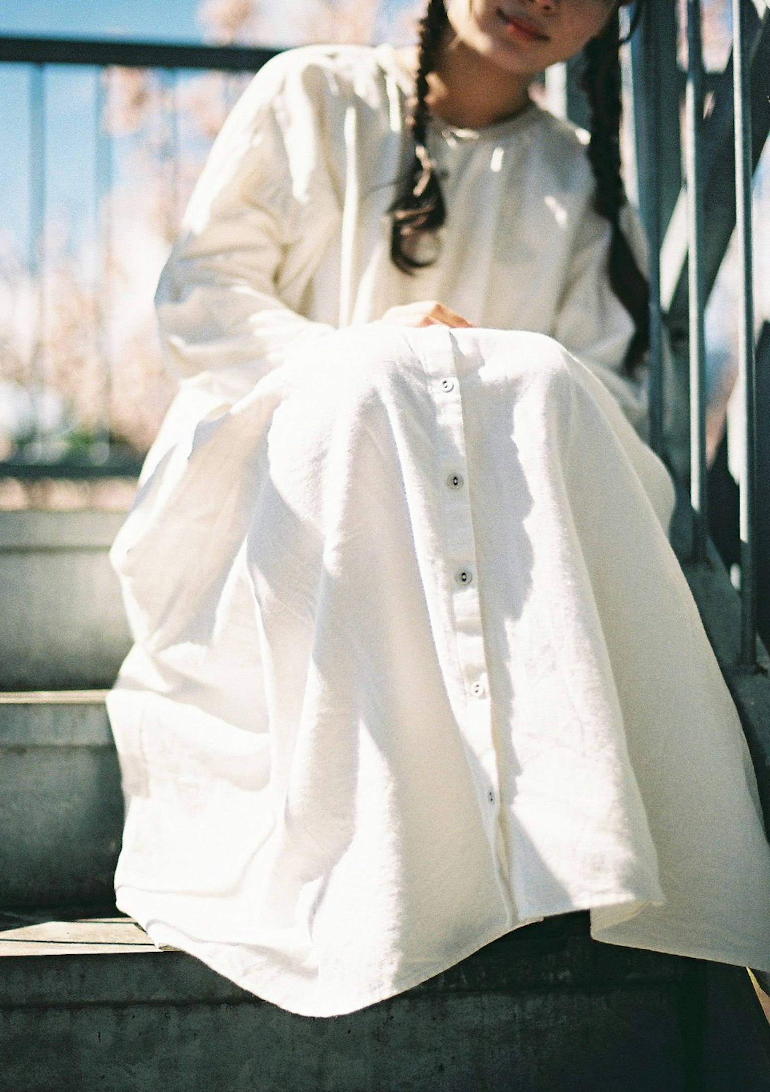 Une fille assise sur des escaliers portant une robe blanche