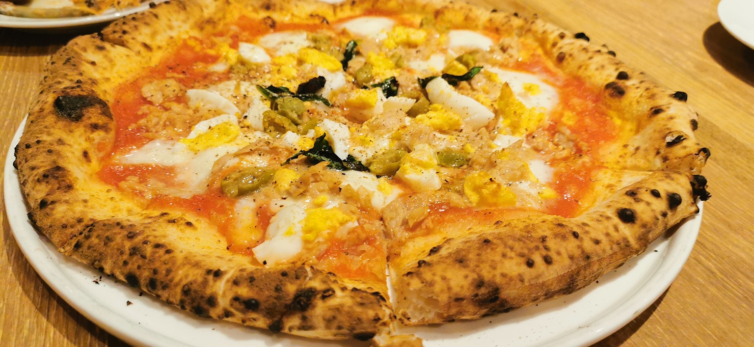 Pizza garnie de sauce tomate œufs et basilic sur une table en bois