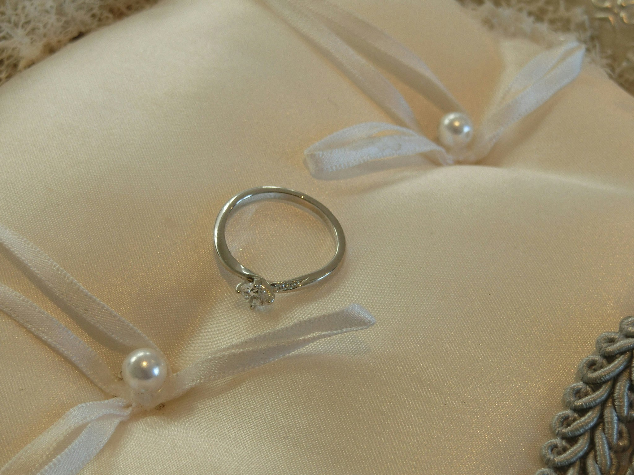 白いリボンとパール飾りの上に置かれた婚約指輪