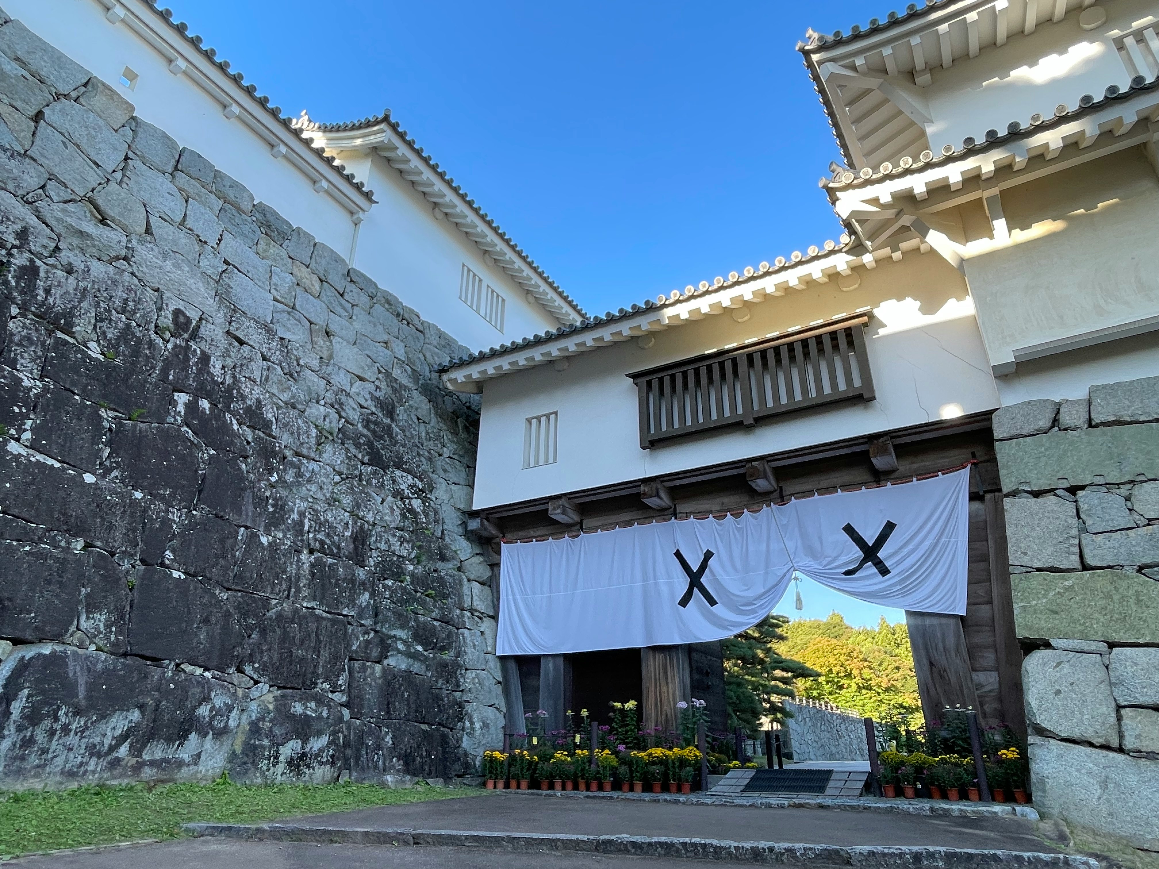 石墙与白色墙面相映的城堡风建筑庭院，蓝天之下的门帘