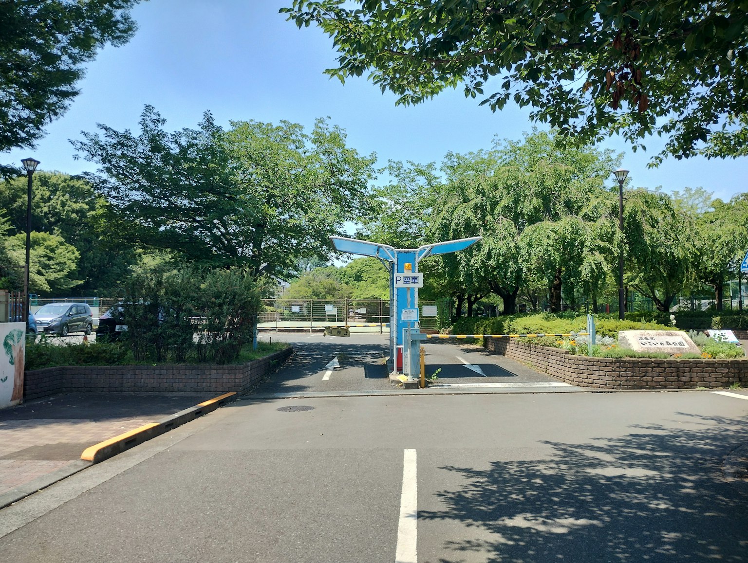 綠色公園的入口，有藍色標誌和周圍樹木