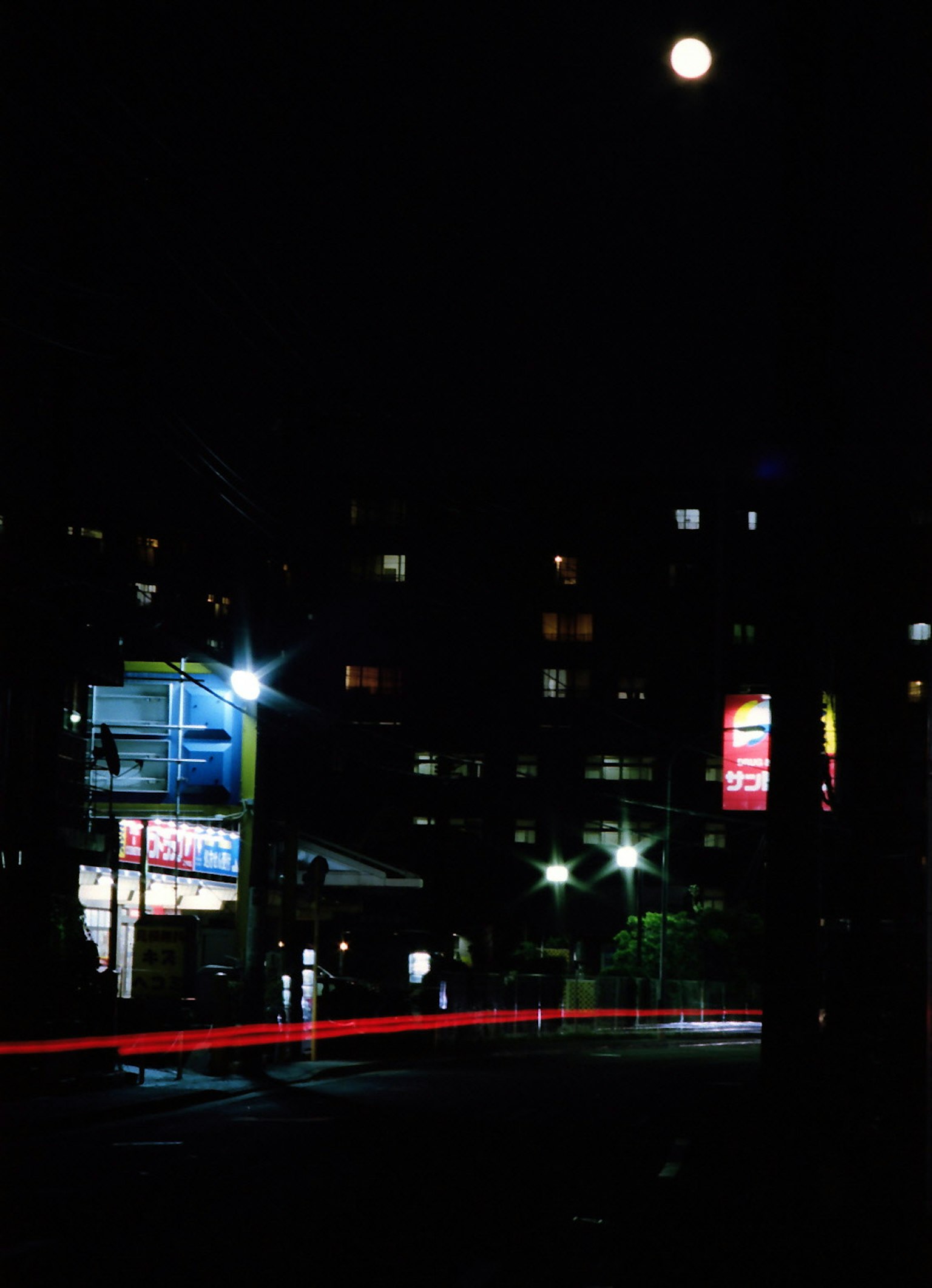 Nächtliche Stadtlandschaft mit hellem Mond und Lichtspuren von Autos
