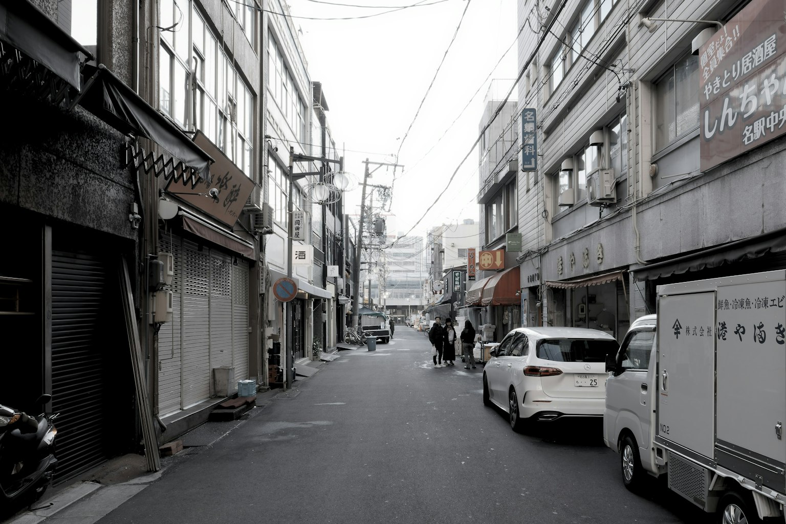Calle estrecha flanqueada por edificios antiguos y coches blancos