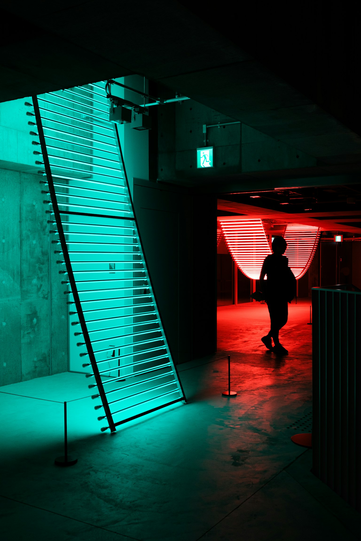 Una silhouette cammina in uno spazio moderno illuminato da luci blu e rosse